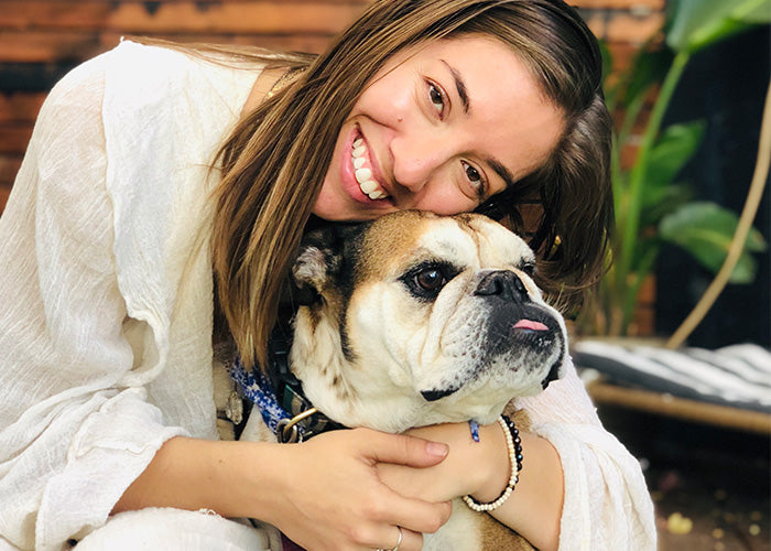 Woman hugging an English Bulldog while smiling, demonstrating the deep bond between humans and pets. Example of how hemp oil extract can support pets' health.